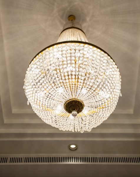 Crystal chandelier shines hanging from the ceiling in the hotel hall